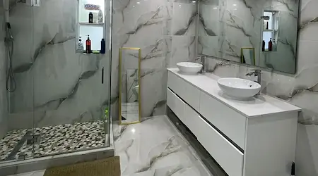 Custom frameless glass shower enclosure with gold hardware in marble bathroom — Fort Myers