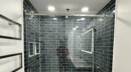 Interior frameless sliding glass barn door with black barn track hardware installed in modern home — Glass Designer LLC Southwest Florida