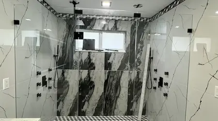 Dual custom frameless shower enclosure with black marble tile and rain shower heads — Naples FL